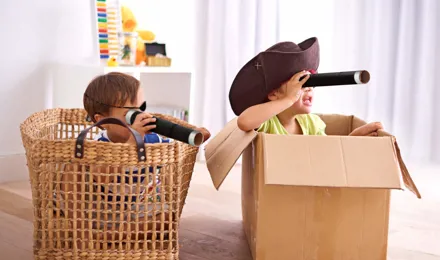 Deux garçons habillés en costumes de pirate qui jouent dans des boîtes en carton et tiennent des longue-vues en carton.