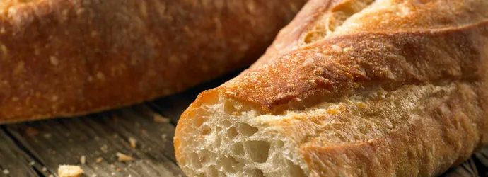 Een gesneden stokbrood met kruimels op een verweerde houten tafel