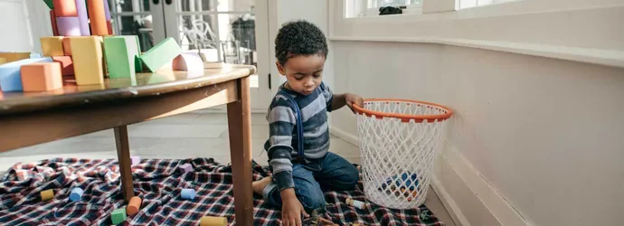 Un enfant sourit tout en nettoyant le sol avec des serviettes en papier