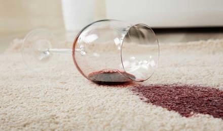 Verre à vin renversé sur un tapis créant une tache de vin