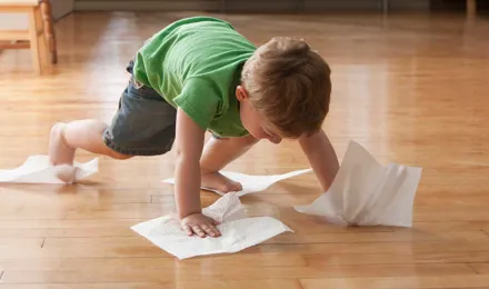 Kind maakt de vloer schoon met keukenpapier