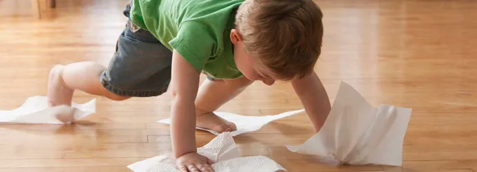 Kind maakt de vloer schoon met keukenpapier