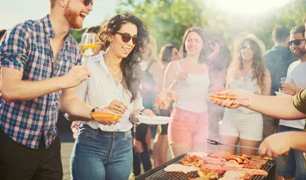 Een groep van vrienden staan op een bbq-feest rondom een ​​bbq-grill