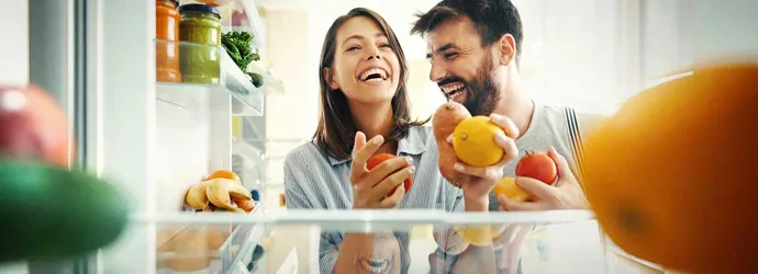 Un couple prend des fruits et des légumes dans le réfrigérateur