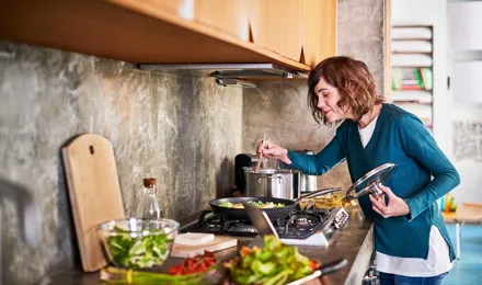 Une femme prépare la nourriture dans une cuisine et fouettant dans une casserole